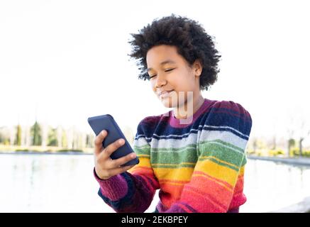 Girl using smart phone while sitting at park Stock Photo