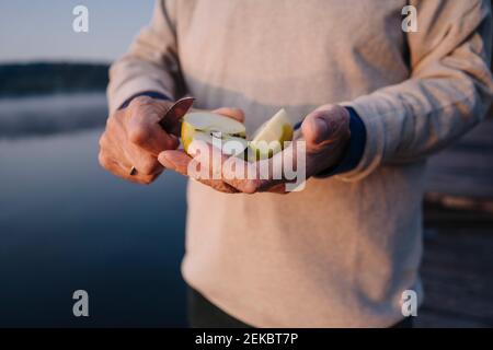 Man holding slice of apple while standing outdoors Stock Photo
