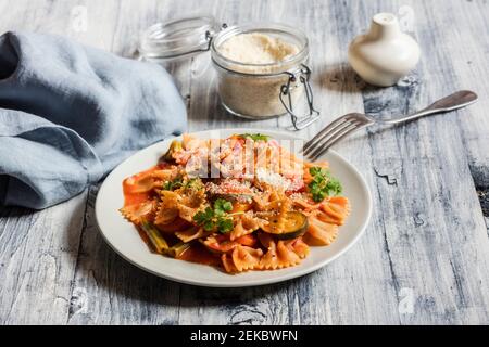 Two plates of bow tie pasta with vegetables and vegan Parmesan Stock Photo