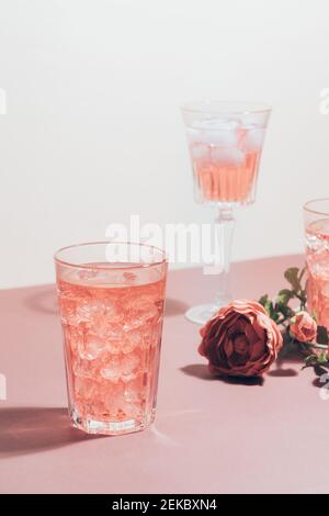 Red drink cocktail or lemonade with ice in a glass on pink background. Stock Photo