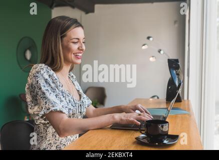 Cheerful female entrepreneur working over laptop on table in restaurant Stock Photo