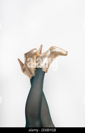 Woman wearing golden stilettos against white background Stock Photo