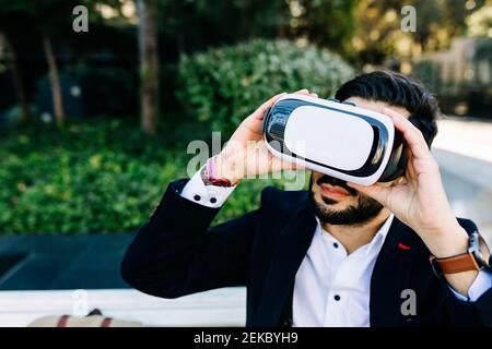 Businessman using virtual reality simulator while sitting outdoors Stock Photo
