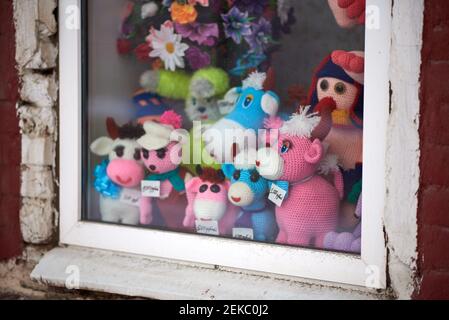 A set of multi-colored knitted toys for sale displayed in a window. Price tags in Russian: 500 rubles, 1000 rubles Stock Photo