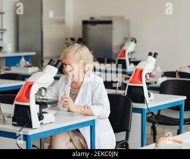 Senior female researcher in a white coat working in lab Stock Photo