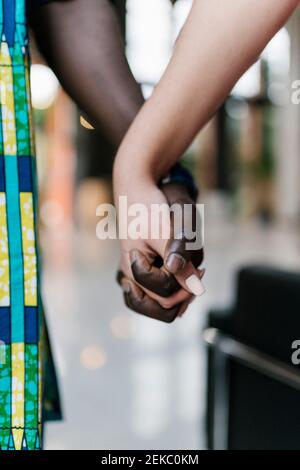 Young man and woman holding hands while standing outdoors Stock Photo
