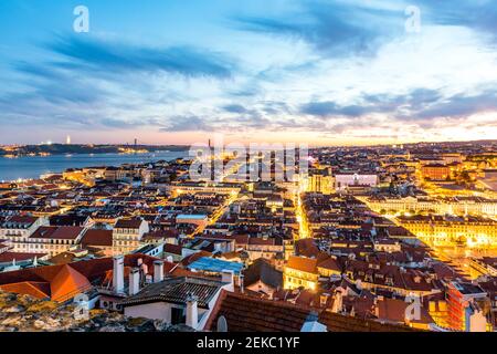 Portugal, Lisbon, View of city with Ponte 25 de Abril on Tagus river in distance at dusk Stock Photo