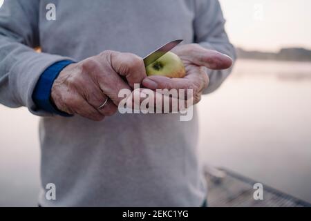 Man cutting apple while standing outdoors Stock Photo