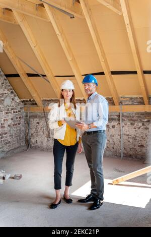 Professional team wearing hardhat working while standing with digital tablet at construction site Stock Photo