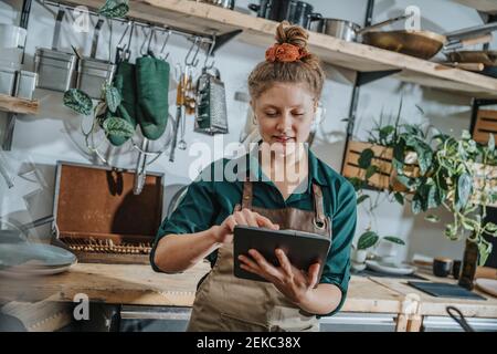 Young chef using digital tablet while standing in kitchen Stock Photo