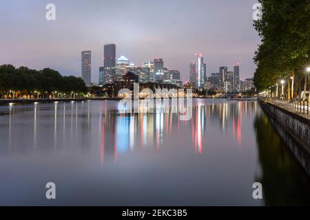 Illuminated skyscrapers reflecting on Thames river against clear sky at dusk, Canary Wharf, London, UK Stock Photo
