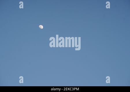 growing moon in clear blue sky during the day. Stock Photo