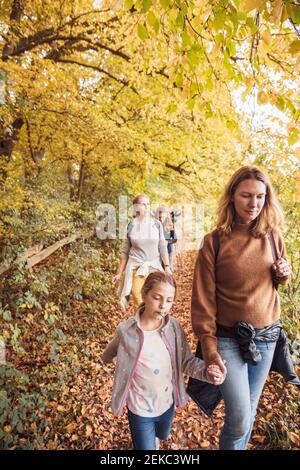 Mature women walking with children while hiking in forest Stock Photo