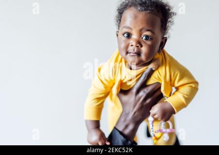 Curious baby girl held by father against wall Stock Photo