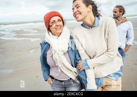 Group of friends walking together along sandy coastal beach Stock Photo