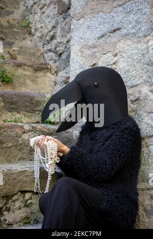Woman in crow costume looking at jewelry by staircase Stock Photo
