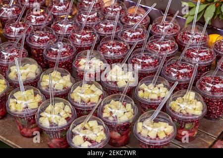 Fruit cocktails in plastic cups stand on shop counter. Stock Photo