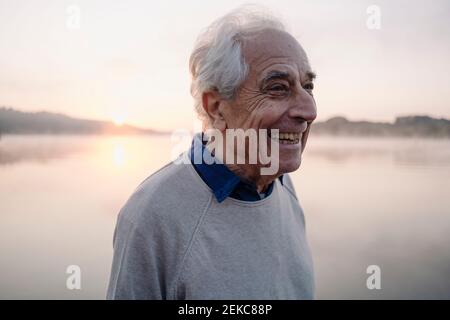 Happy man looking away while standing against lake Stock Photo