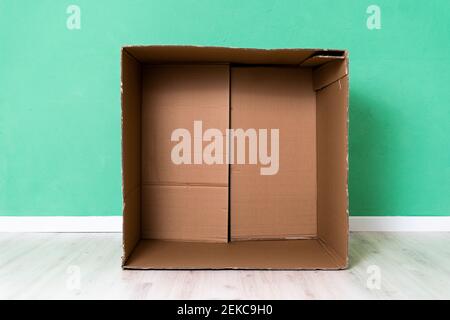 Empty cardboard box against green wall in apartment Stock Photo