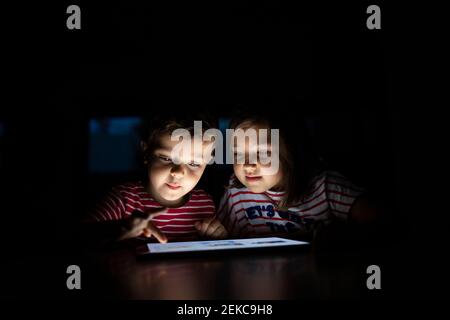 Brother using digital tablet by sister at home Stock Photo