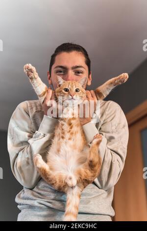 Young man playing with cat at home Stock Photo