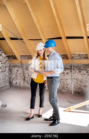 Colleagues wearing hardhat using digital tablet while standing at construction site Stock Photo