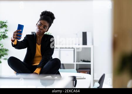 Afro female professional taking selfie through smart phone in office Stock Photo