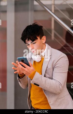 Man with headphones using mobile phone while standing outdoors Stock Photo
