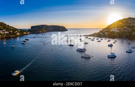 Spain, Balearic Islands, Andratx, Helicopter view of boats sailing near shore of coastal town at sunset Stock Photo