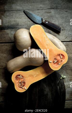 Butternut pumpkins (Cucurbita moschata) cut in halves against rustic background Stock Photo