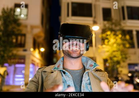 Happy man using virtual reality headset while sitting outdoors Stock Photo