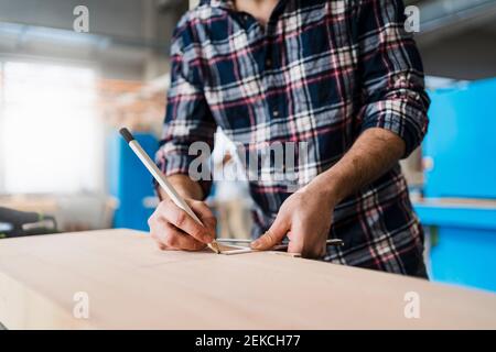 Manual worker measuring wood while working at industry Stock Photo