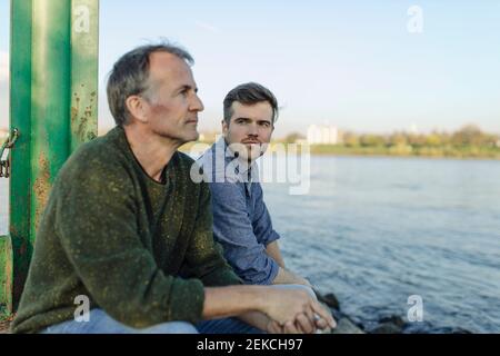 Son looking at thoughtful father by river Stock Photo
