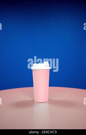 Reusable coffee cup on table against blue background Stock Photo