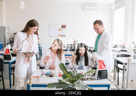 Students and teacher in white coats discussing in science class Stock Photo