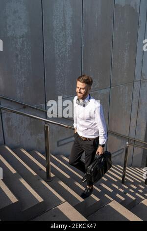 Businessman with briefcase moving up on steps Stock Photo