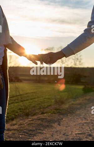 Heterosexual couple holding hands during sunset Stock Photo