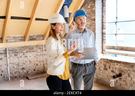 Businesswoman explaining to engineer standing with digital tablet at construction site Stock Photo