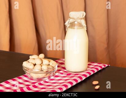 Glass bottle with peanut milk and peanuts in the shell. Lactose-free milk, vegetarianism. Stock Photo