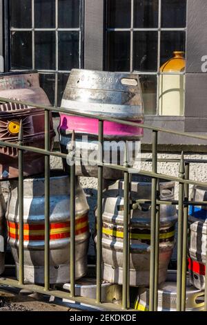 Metal beer casks piled up outside a pub for collection and reuse. Stock Photo