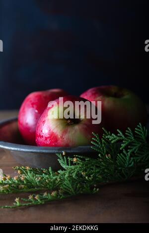 Fresh red apples in plate on wooden table. Stock Photo