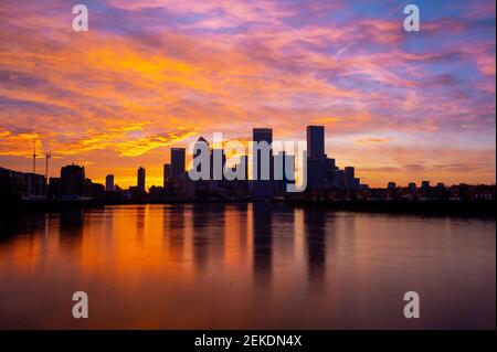 Spectacular sunrise over Canary Wharf, financial capital of UK, London with the River Thames in the foreground reflection the purple and yellow sky Stock Photo