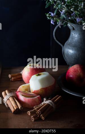 Fresh apples in plate with cinnamon sticks on natural wooden background. Stock Photo