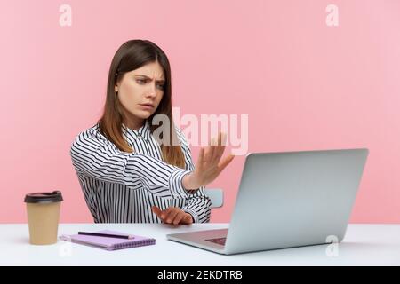 Serious concerned woman office worker showing stop gesture to laptop screen, warning with prohibition sign talking on video call, online communication Stock Photo