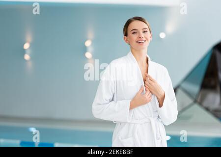 joyful young woman adjusting bathrobe in spa center Stock Photo