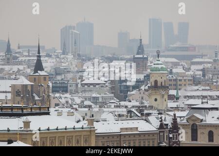 Pankrác skyscrapers raised behind the snow covered historical centre of Prague pictured from the Hanavský Pavilon in Letná Park (Letenské sady) in Prague, Czech Republic. The skyscrapers pictured from left to right: Corinthia Hotel, City Empiria (Motokov Building), Panorama Hotel, City Tower and V Tower. The church of Saint Giles (Kostel svatého Jiljí), the New Town Hall (Novoměstská radnice) and the Astronomical Tower of the Clementinum (Klementinum) are seen from left to right in the foreground. Stock Photo