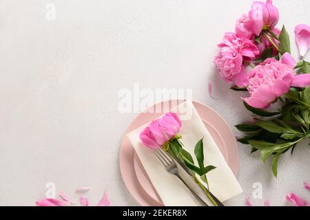 Spring romantic table setting with pink peony flowers on a white table. Stock Photo