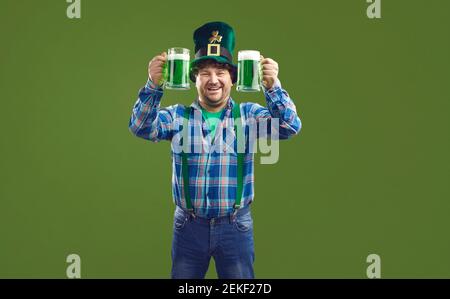 Happy man celebrating Saint Patrick's Day and drinking green beer from two glasses Stock Photo