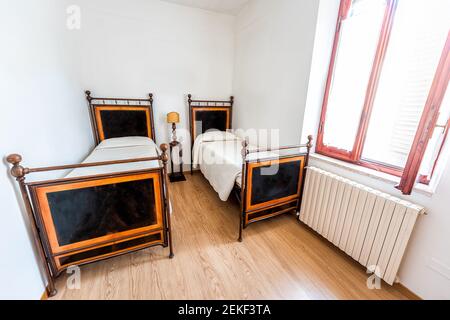 Rustic antique old-fashioned Italian country home house cottage bedroom in villa with two twin mattress beds and wooden floor with window Stock Photo