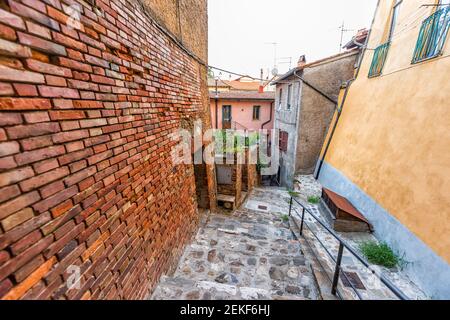 Chiusi, Italy road narrow empty alley street in small historic town village in Tuscany colorful brick wall of houses and garden plants Stock Photo